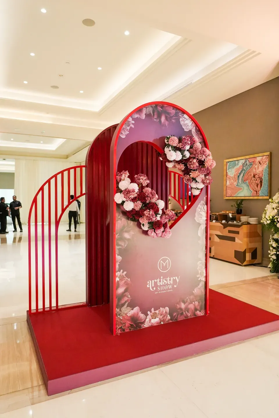 Side view of a red floral arch and its mirrored panel on a carpeted riser