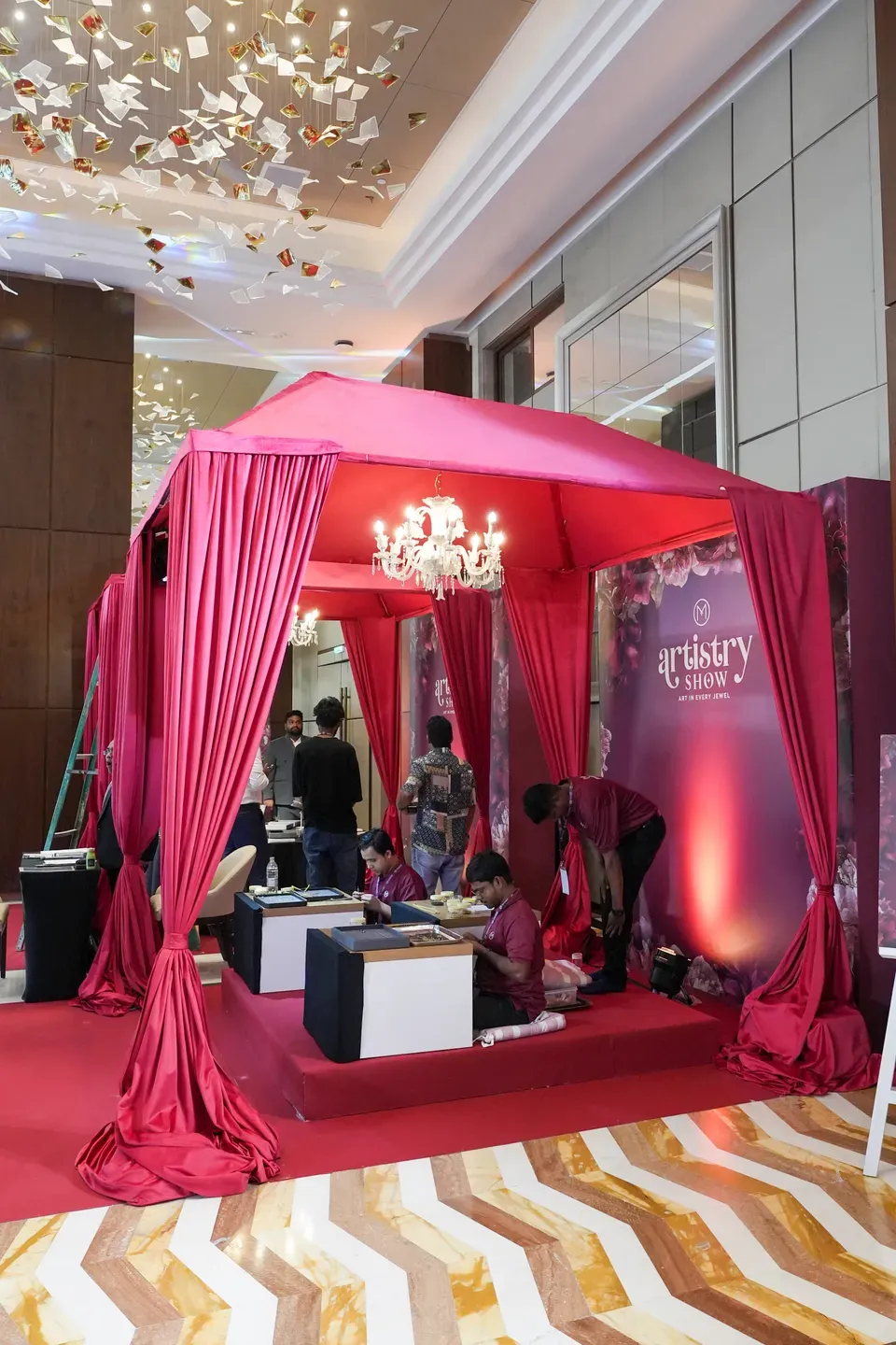 Deep pink draped cabana with a crystal chandelier housing a consultation area