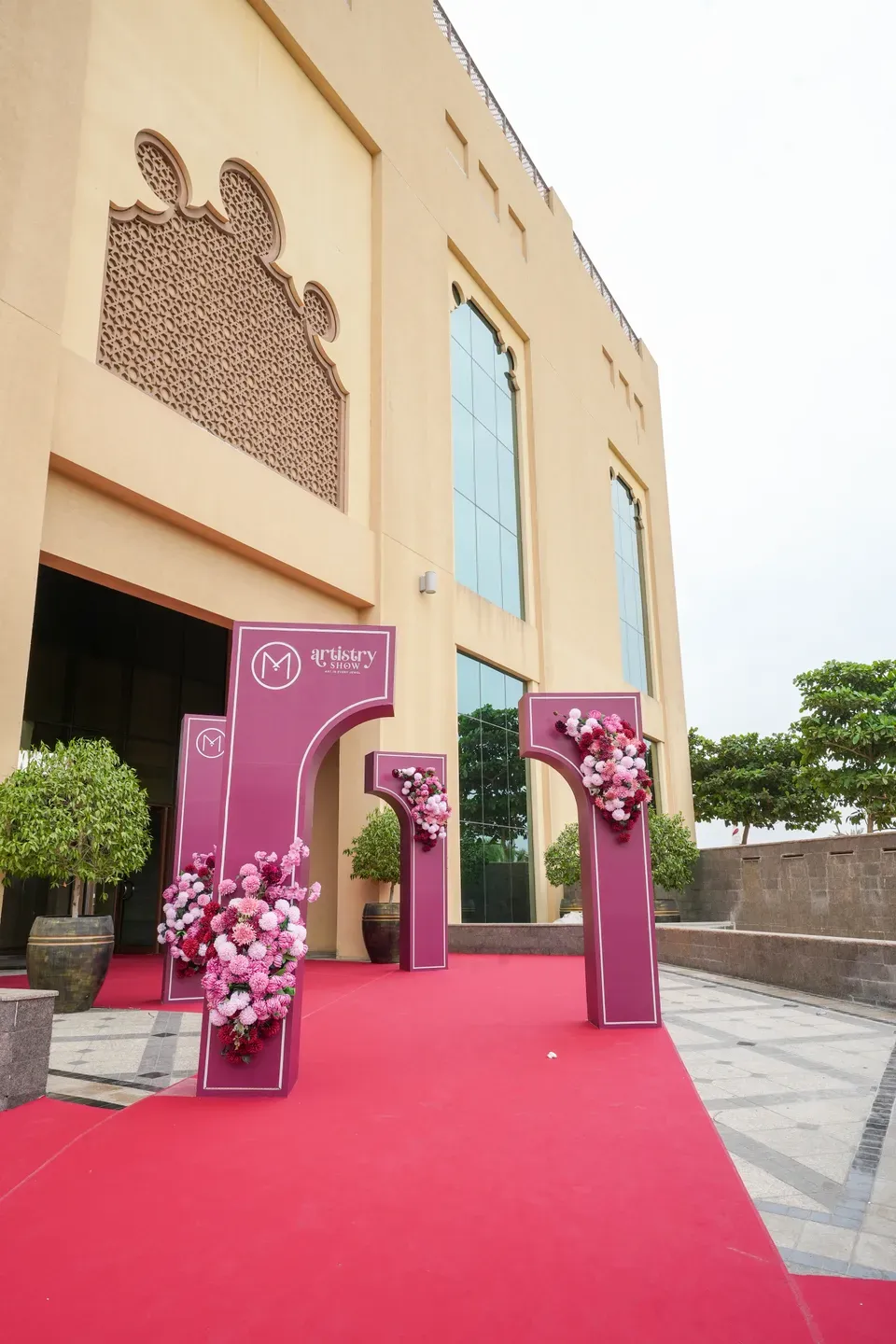 Two burgundy floral totems on a red carpet outside a hotel entrance