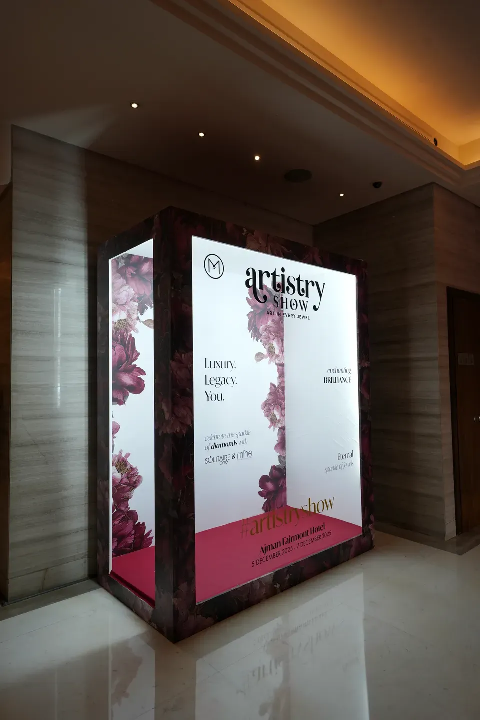 Tall illuminated lightbox column carrying event details in a hotel corridor