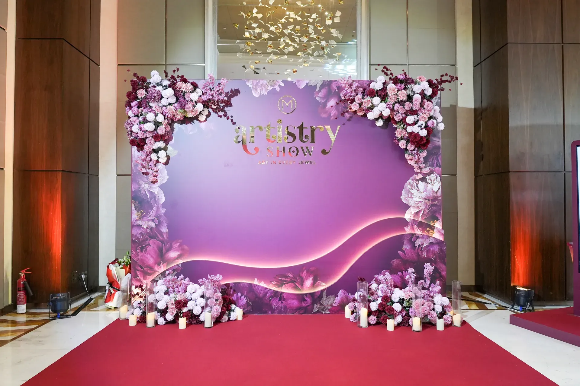 Lilac floral photo backdrop on a red carpet flanked by branded gift boxes