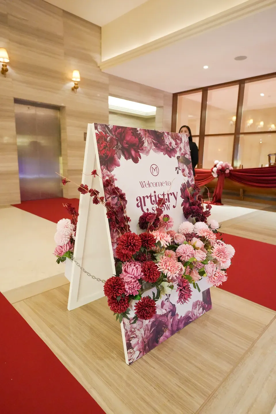 Floral-printed welcome board on an easel banked with pink and burgundy dahlias