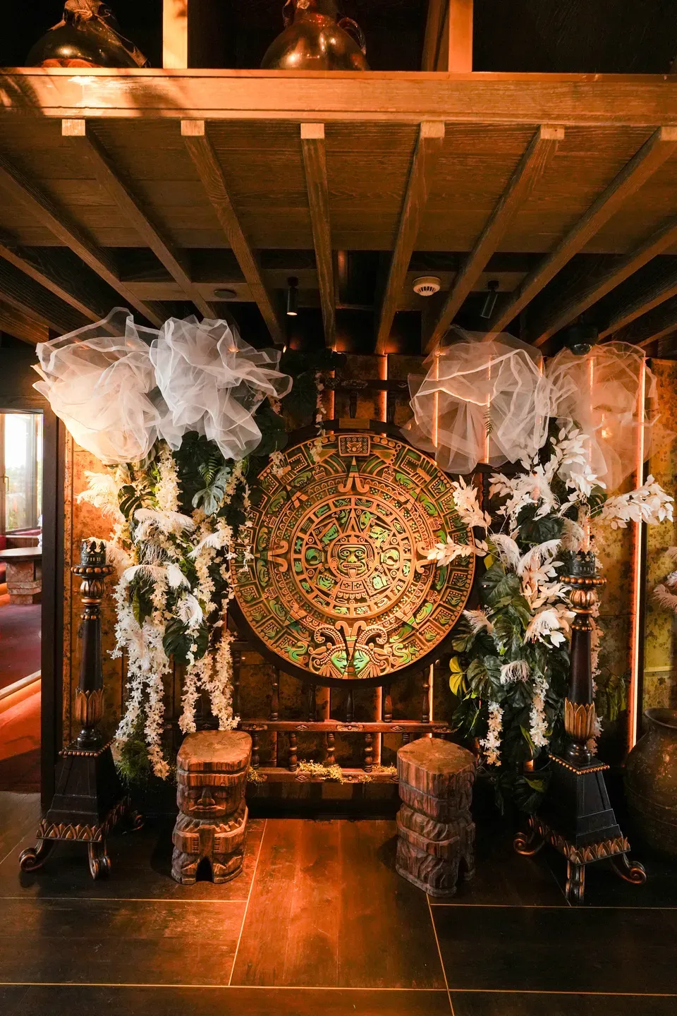 Carved circular wall disc flanked by white floral columns and tulle puffs