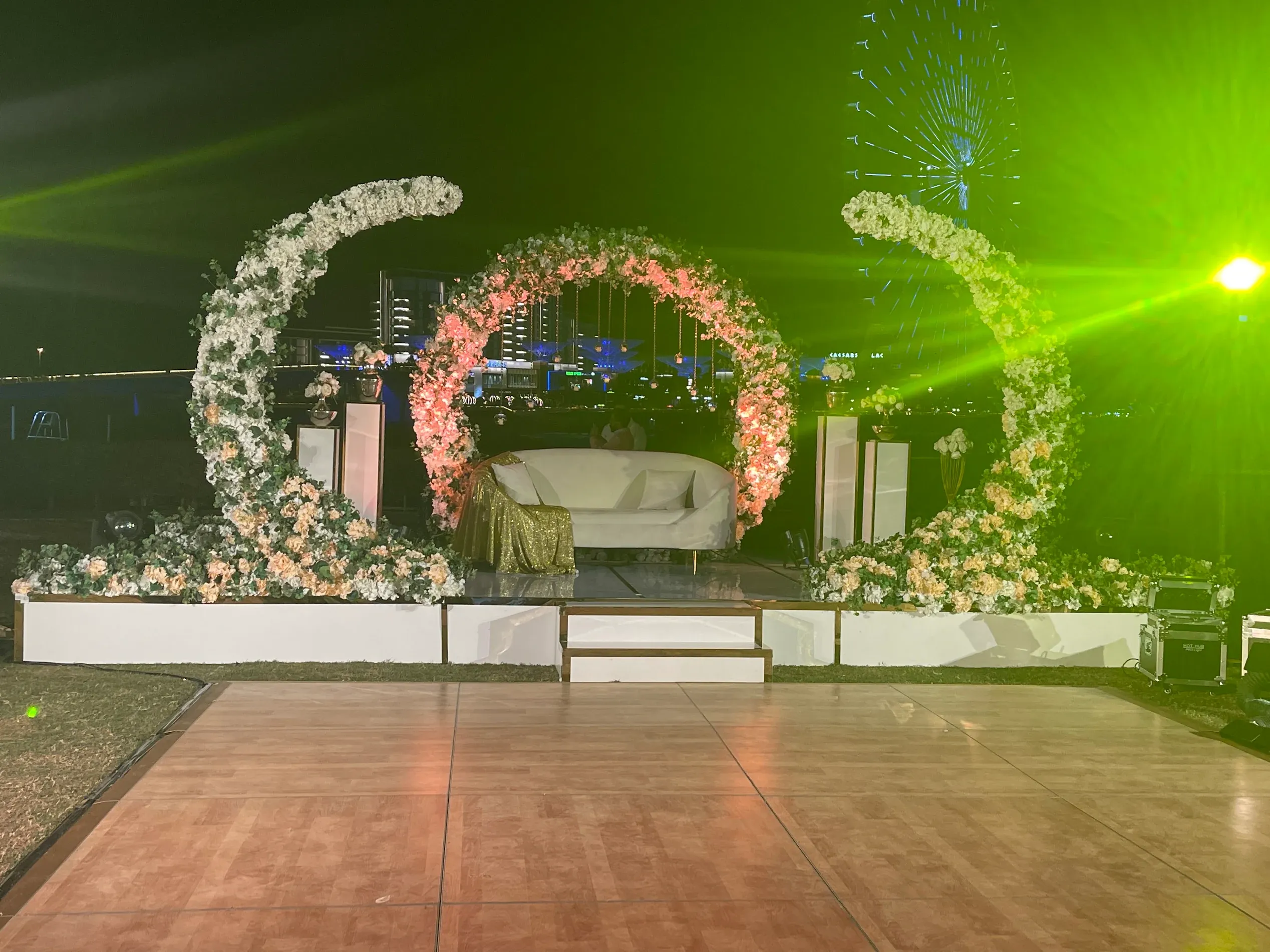 Crescent floral stage and parquet dance floor under green wash lighting, Ain Dubai in the distance