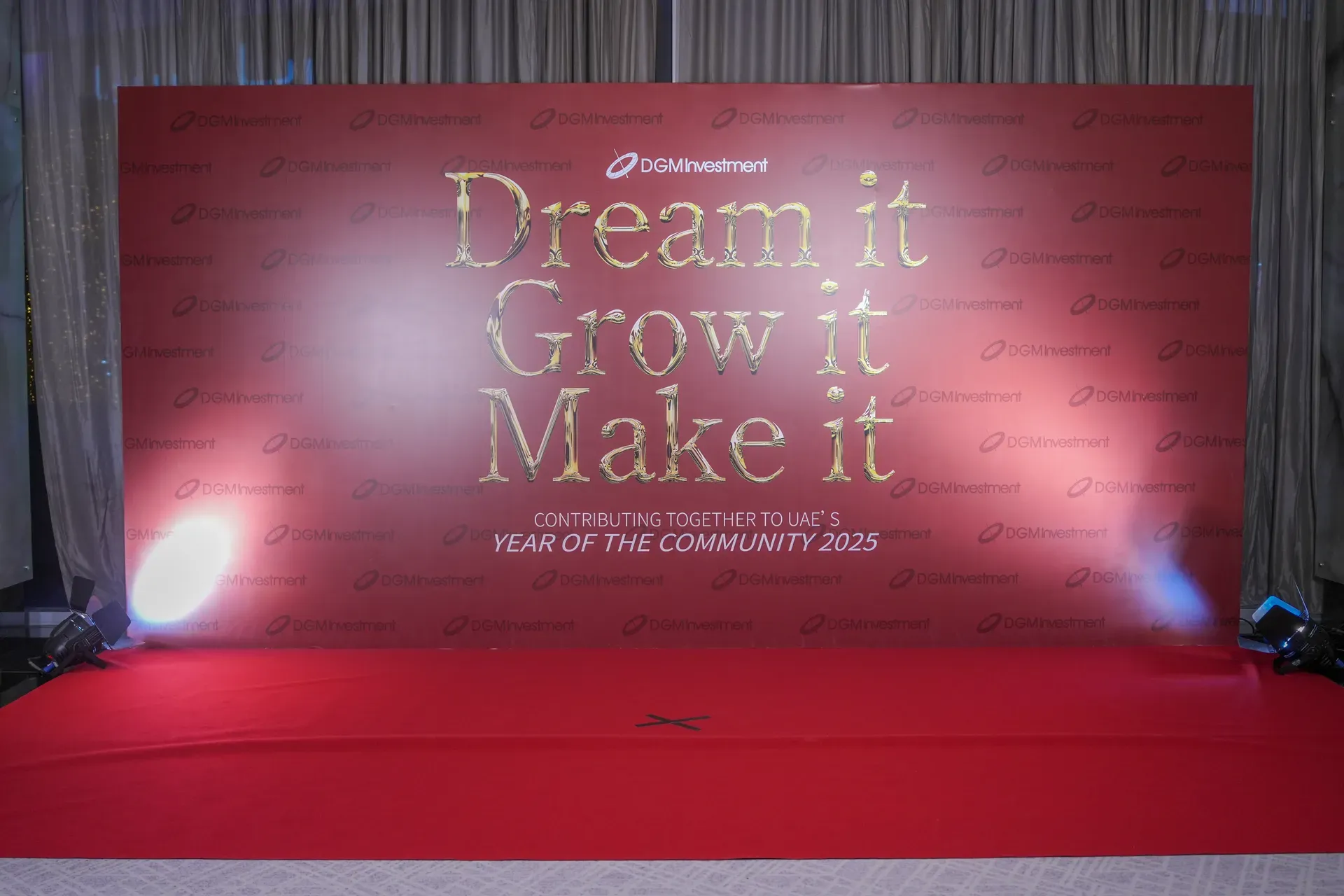 Red branded backdrop in gold lettering with a red carpet runner in front