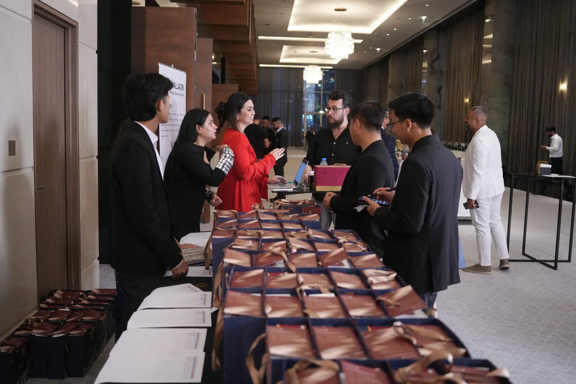 Guests collecting wrapped gifts from a long table staffed at a hotel entrance