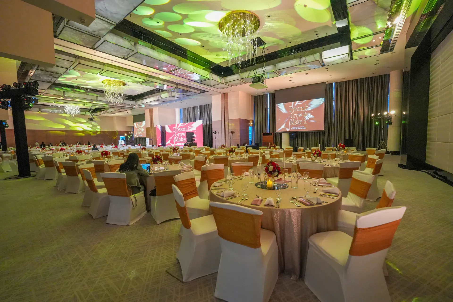 Banquet rounds in copper and cream under green foliage gobos projected across the ceiling