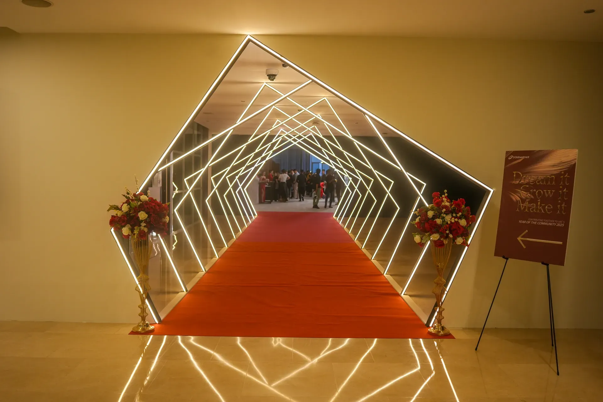 Angular neon-lit tunnel over a red carpet leading into the event floor