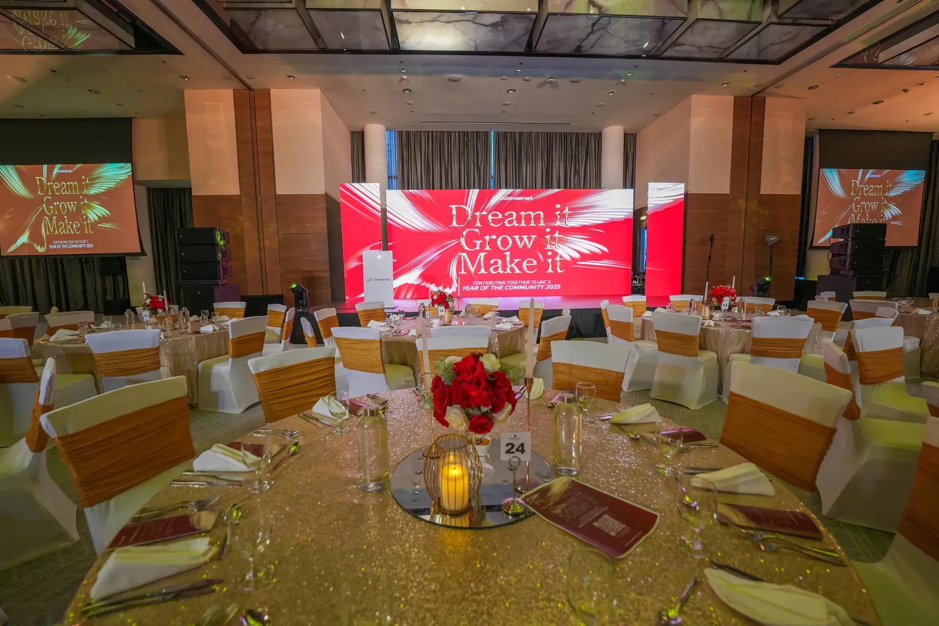 Red main stage screen flanked by two side screens above set banquet tables