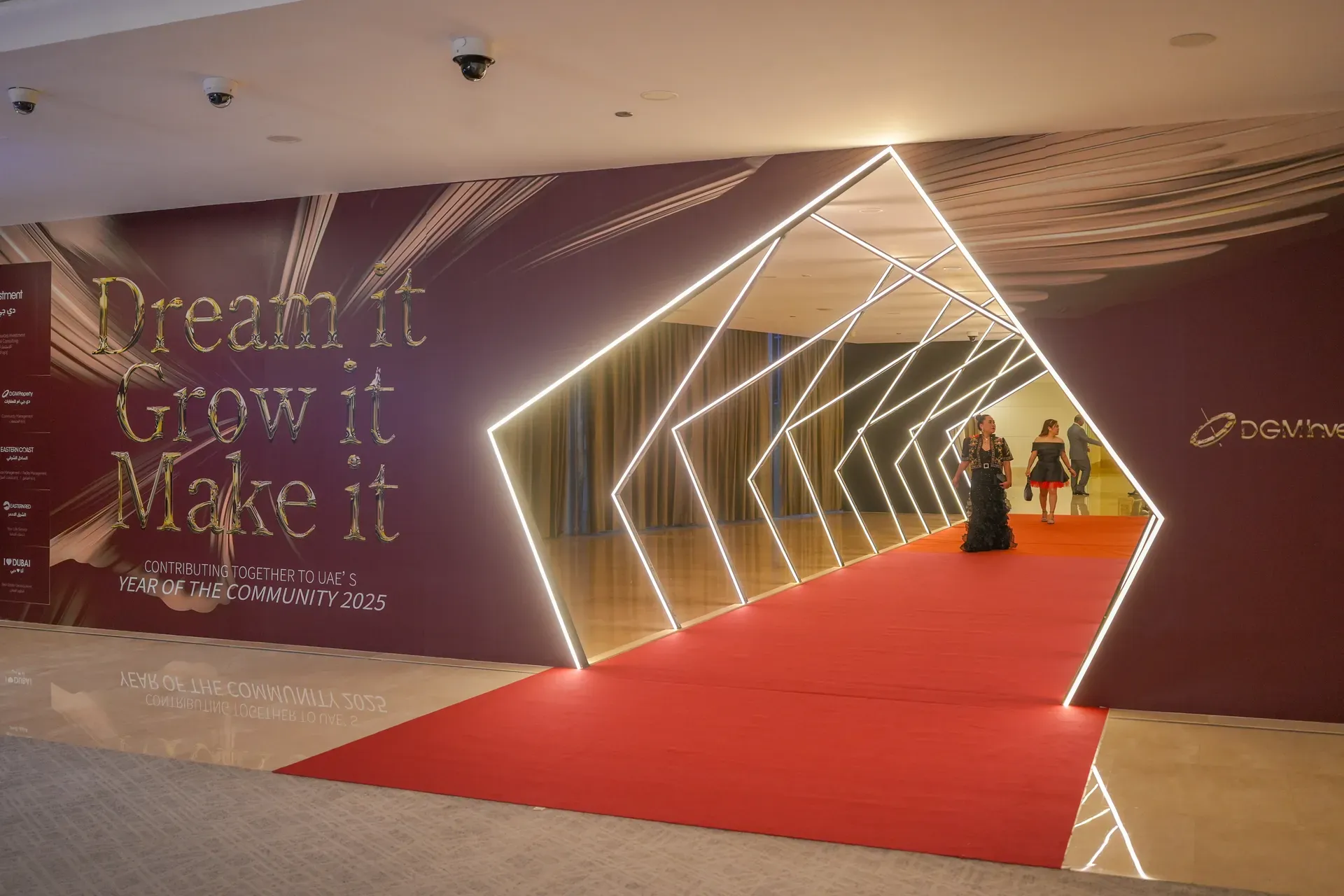 Red carpet running through a lit angular frame tunnel against a printed wall