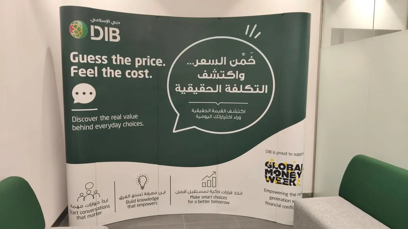 Green curved pop-up display wall printed in English and Arabic in a branch interior
