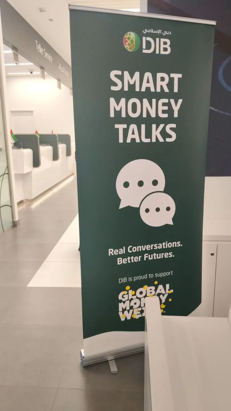 Green roll-up banner reading Smart Money Talks standing in a bank branch