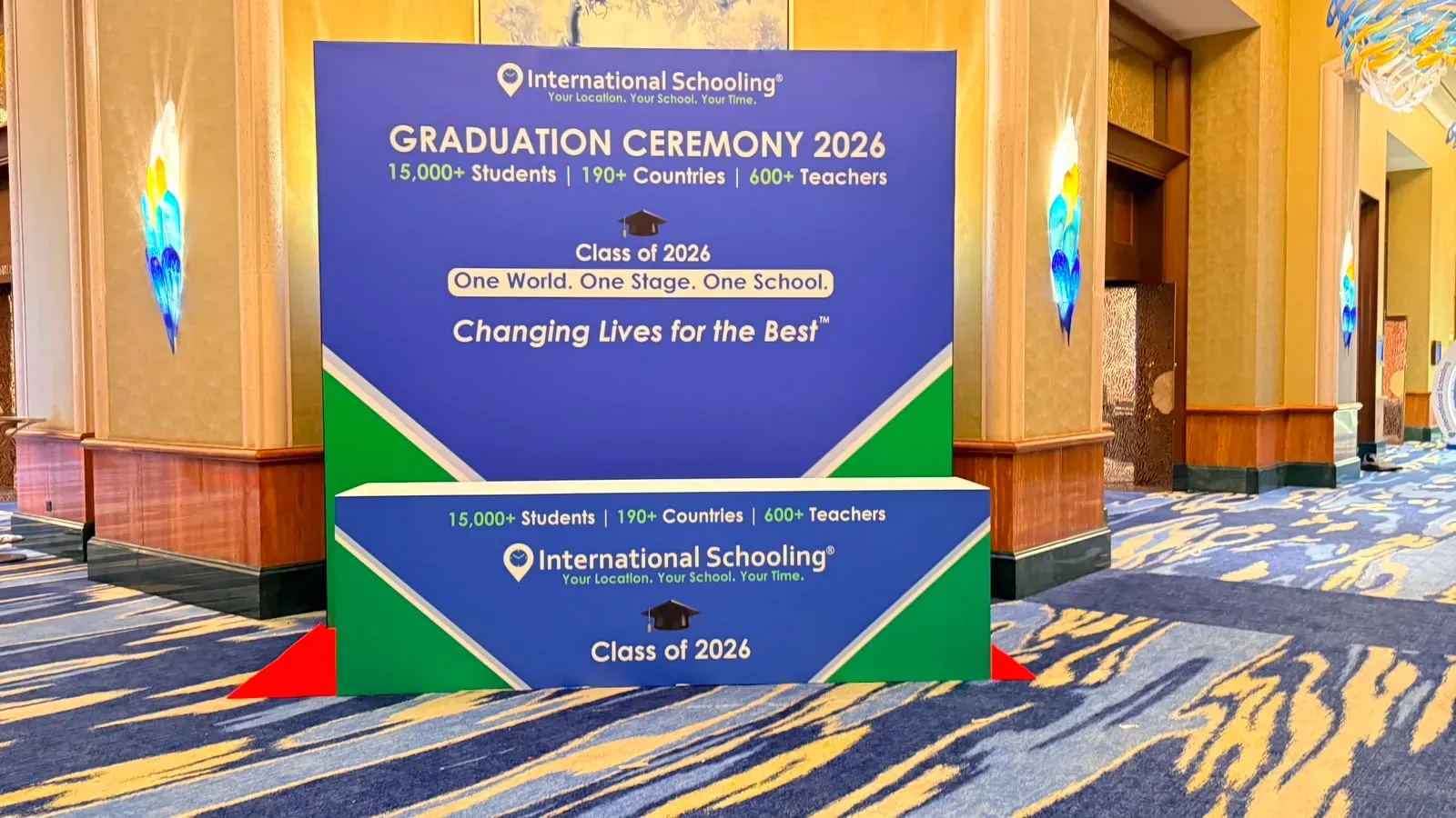 Blue and green branded backdrop for a graduation ceremony on a patterned carpet