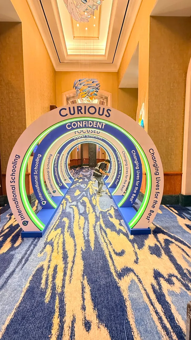 Concentric lettered arches over a blue runner leading down a hotel corridor