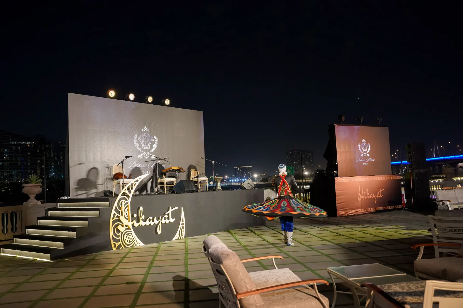 Rooftop stage with a gold crescent logo and a tanoura dancer spinning on the terrace