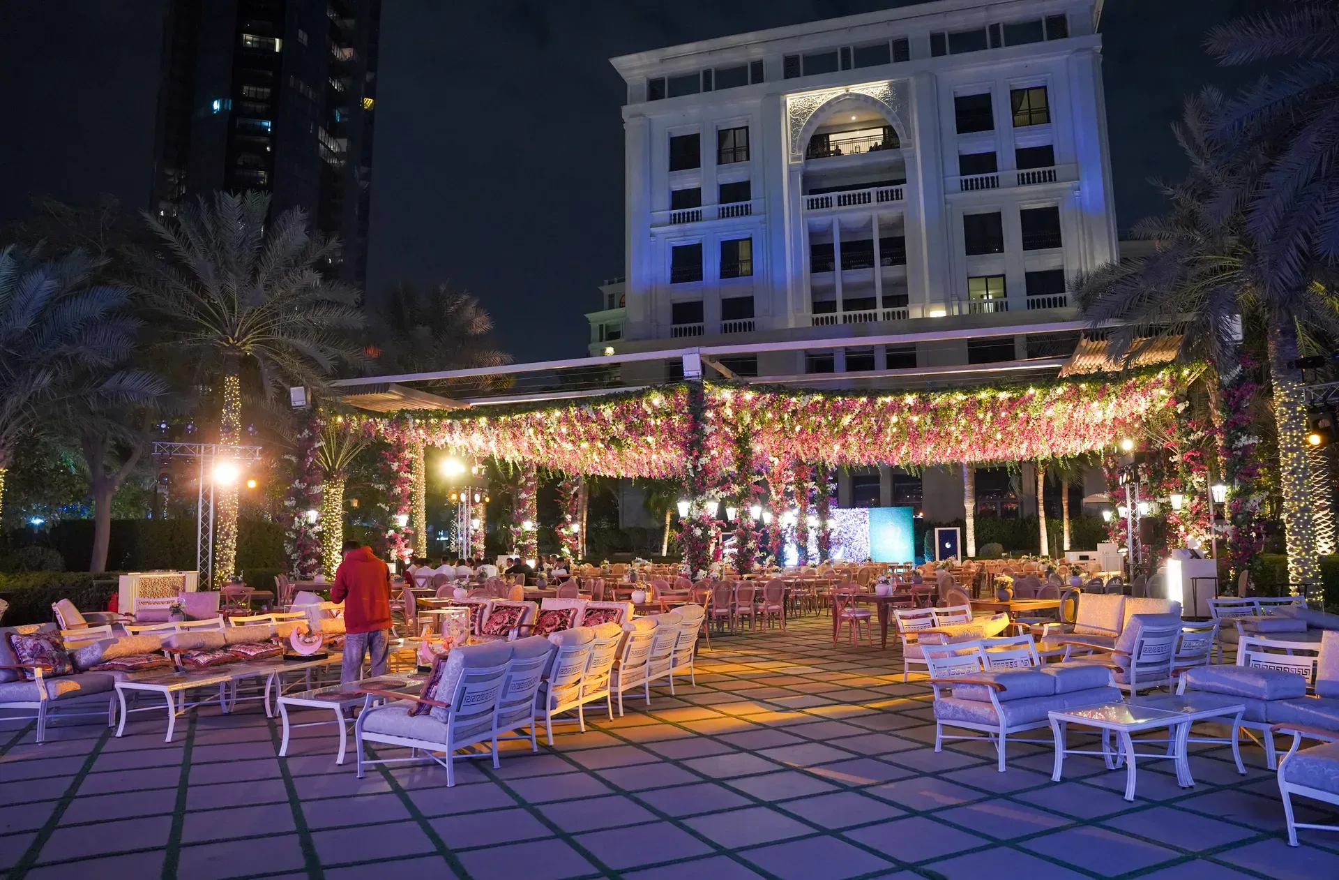 Outdoor terrace lounge beneath a lit canopy threaded with blossom and fairy lights