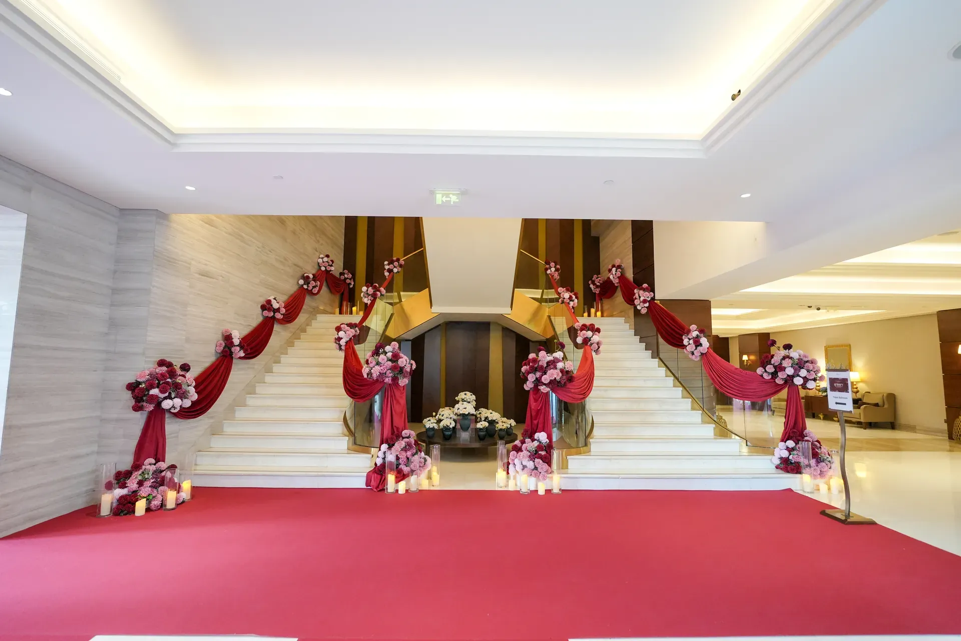Hotel staircase dressed with burgundy swags and floral clusters over a red carpet