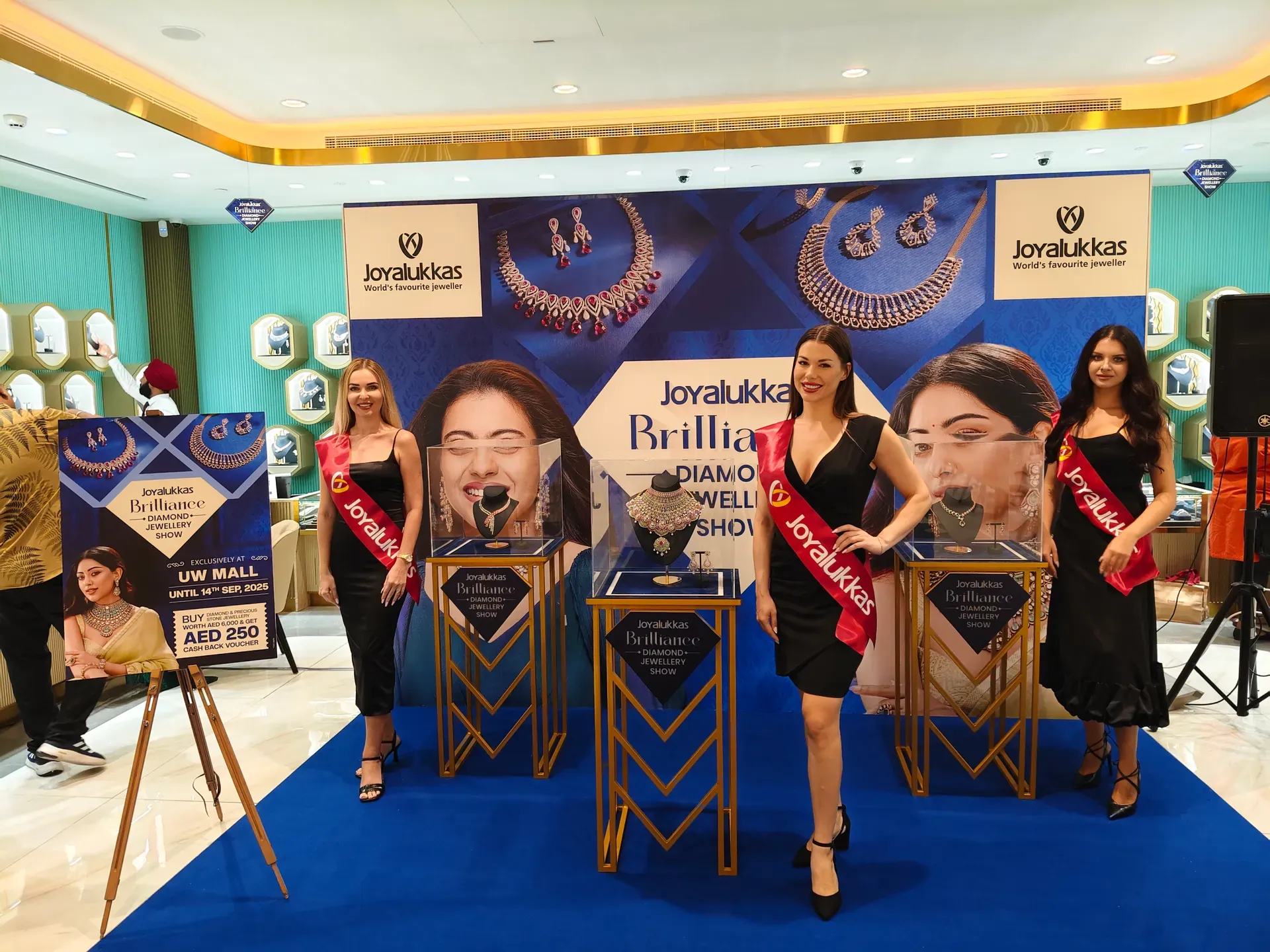 Hostesses beside lit display plinths at the Joyalukkas Brilliance jewellery showcase