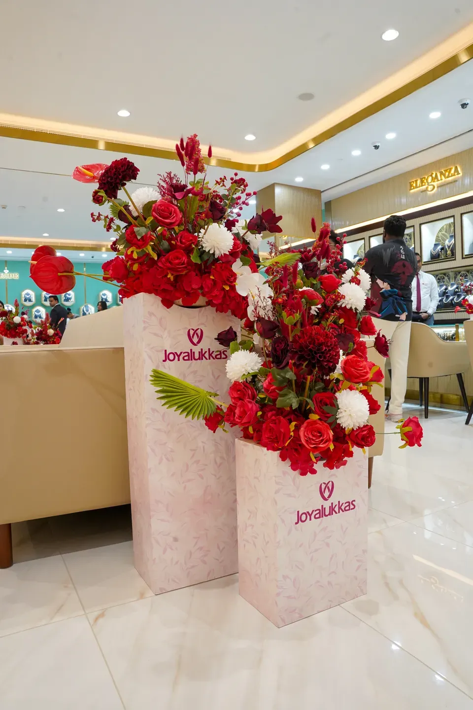 Two blush branded plinths with red anthurium and chrysanthemum arrangements