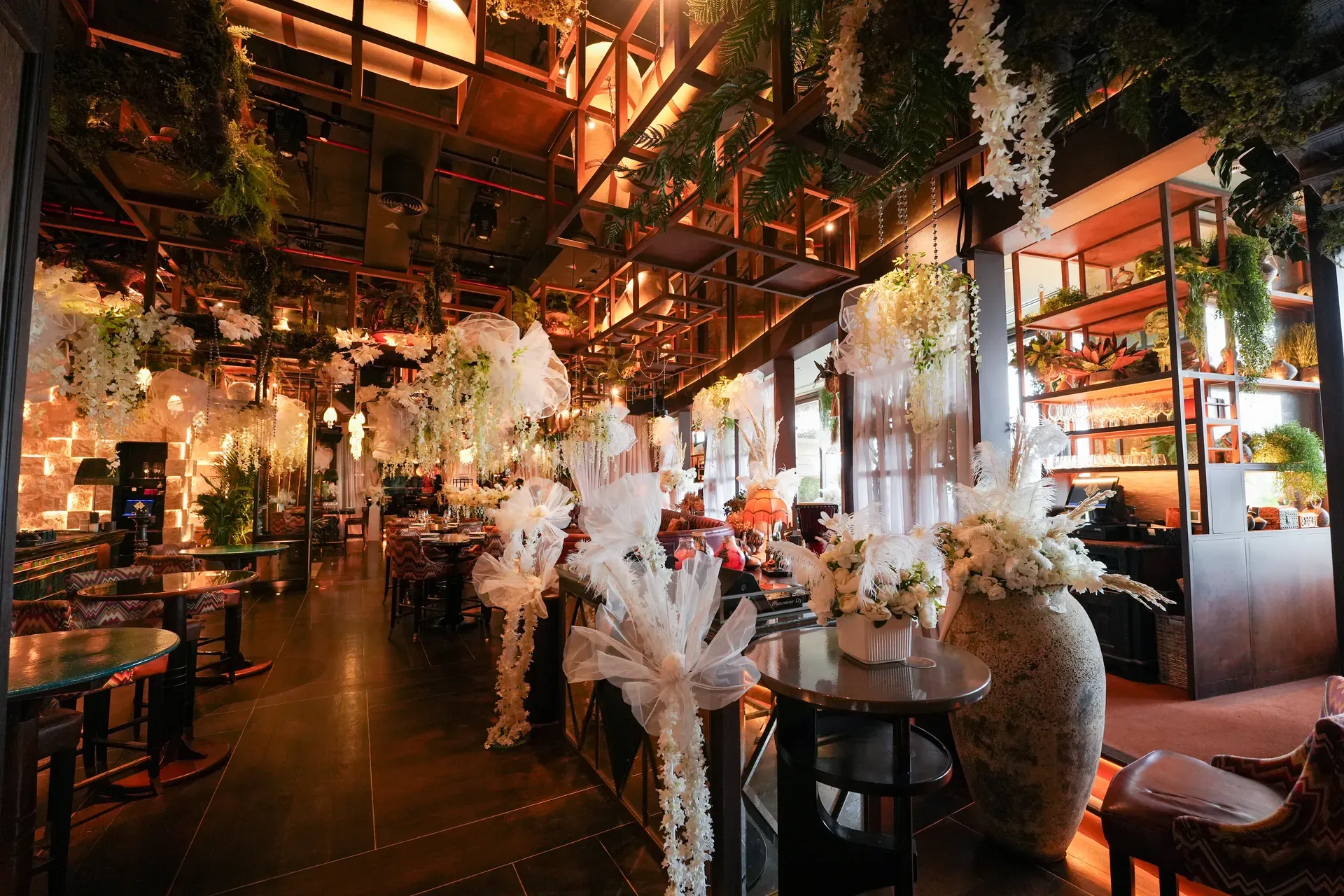 Restaurant floor dressed with white feather and orchid arrangements before guests arrive