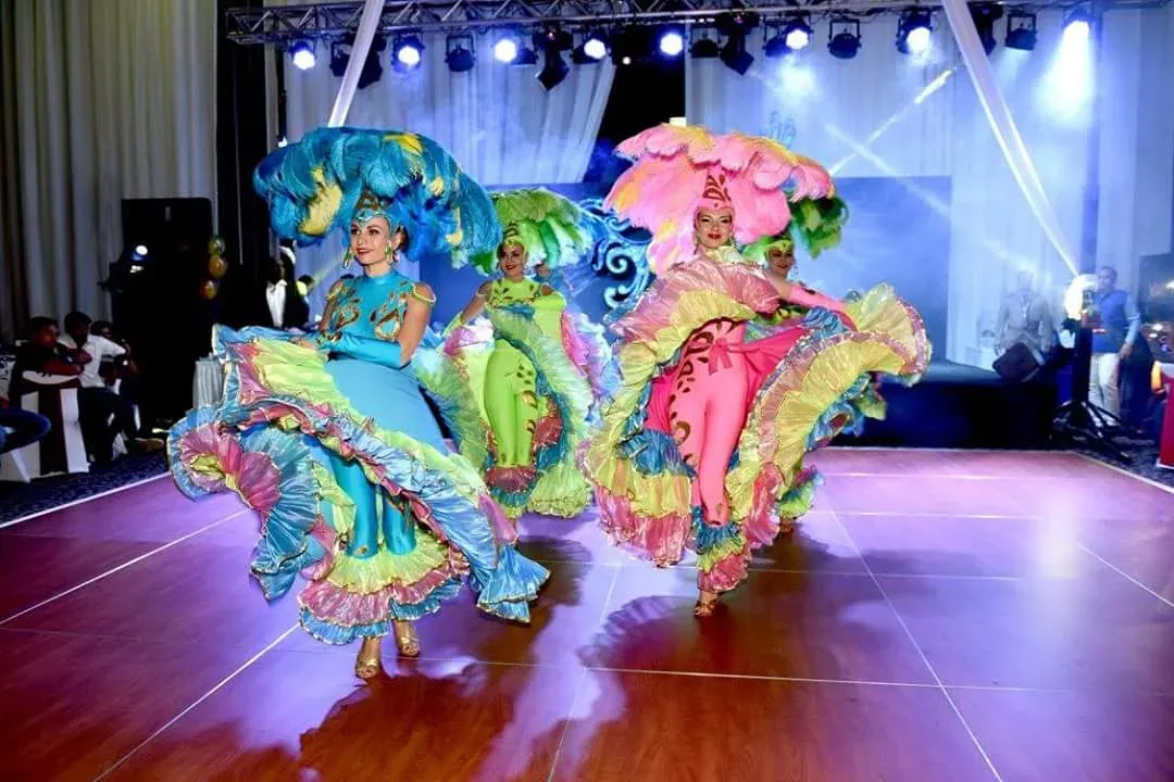 Three dancers in multicoloured ruffled dresses turning on a wooden dance floor