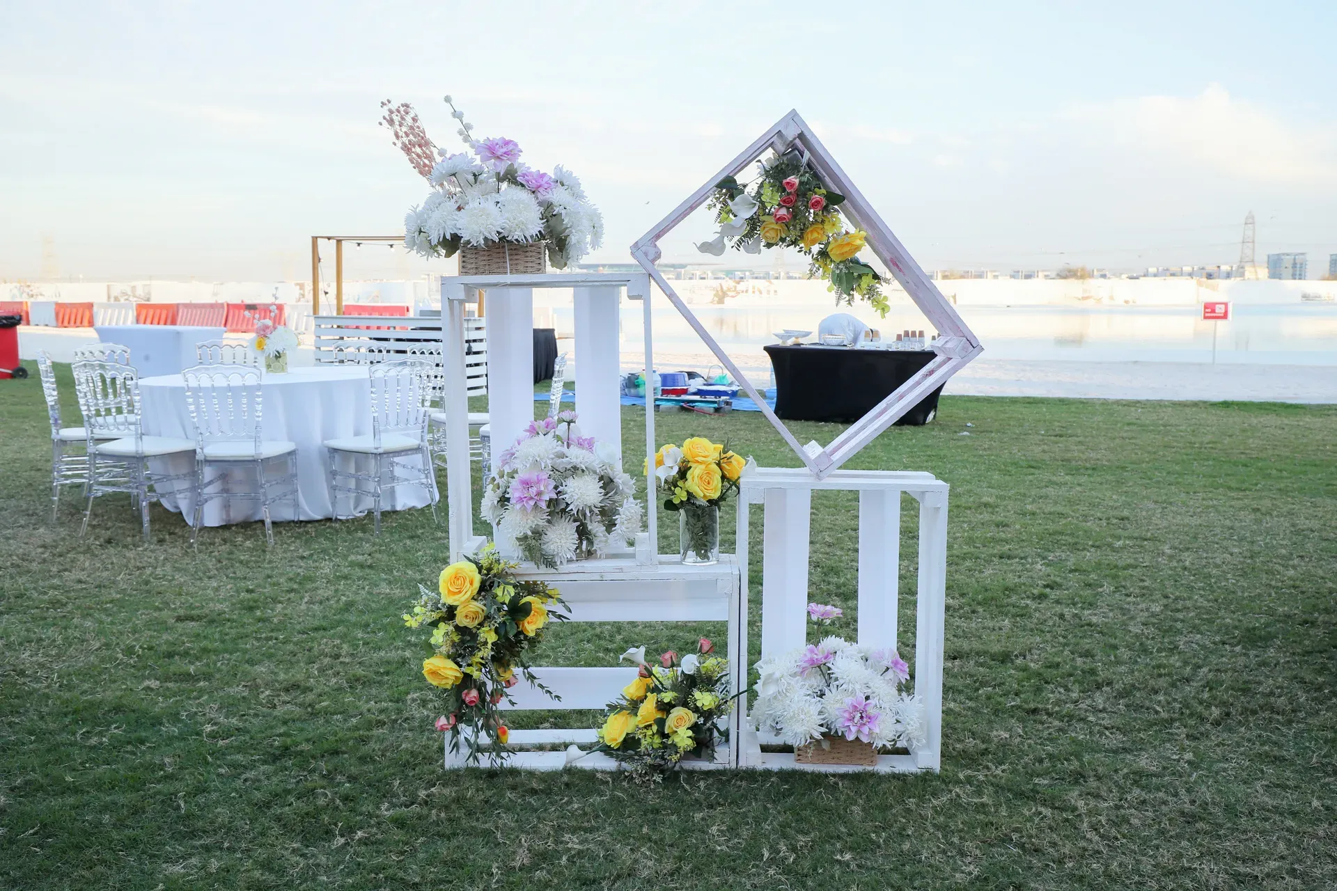 White timber flower cart massed with pastel blooms beside banquet rounds on grass