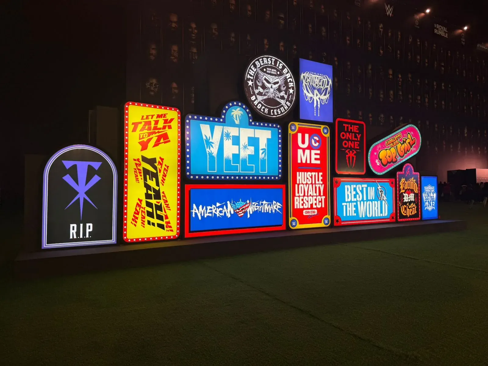 Wall of illuminated slogan lightboxes in bright colours set up on a lawn at night