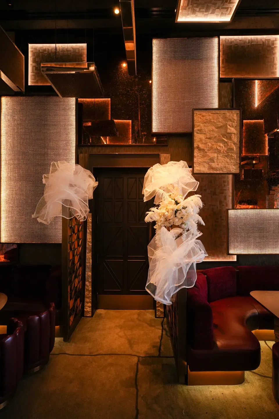 Two tulle installations hanging above leather banquettes in a low-lit lounge