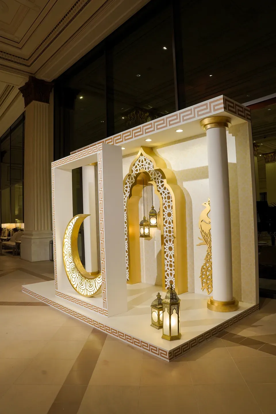 White and gold set piece with a crescent, lanterns and fretwork arches in a hotel lobby