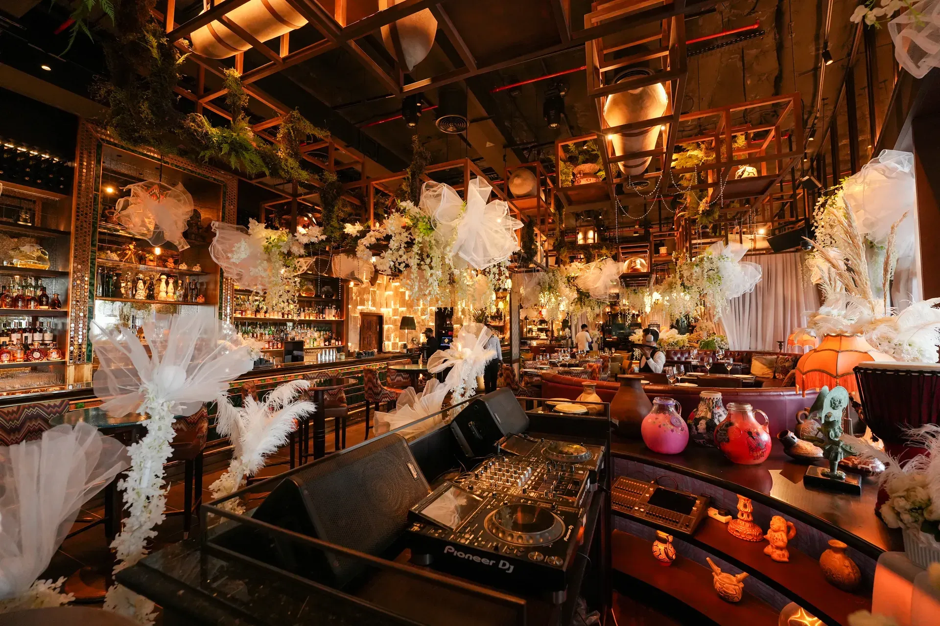 Bar counter and stools with white tulle and dried-grass arrangements along the front