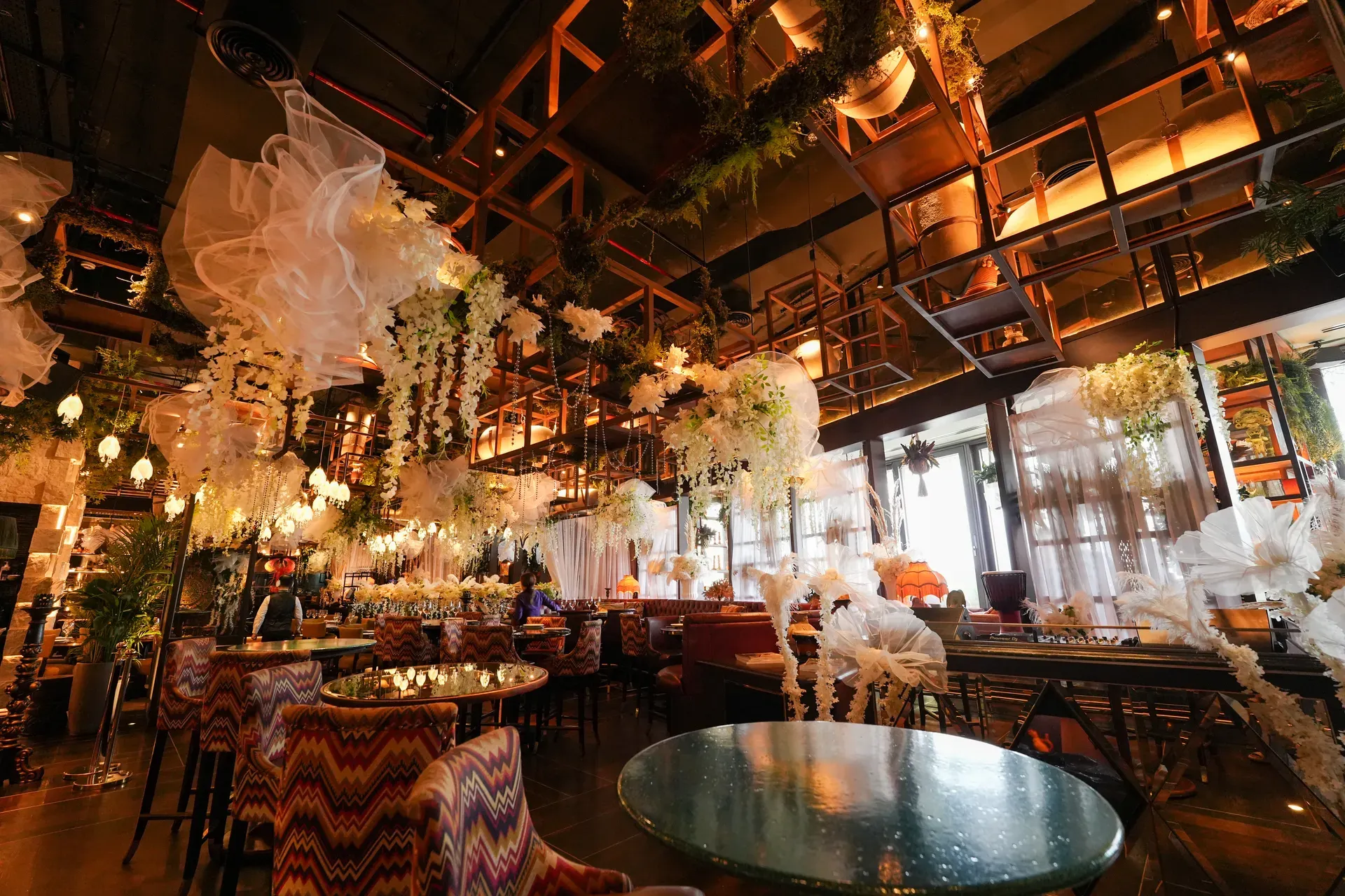 Bar and lounge seating below suspended tulle puffs and hanging greenery