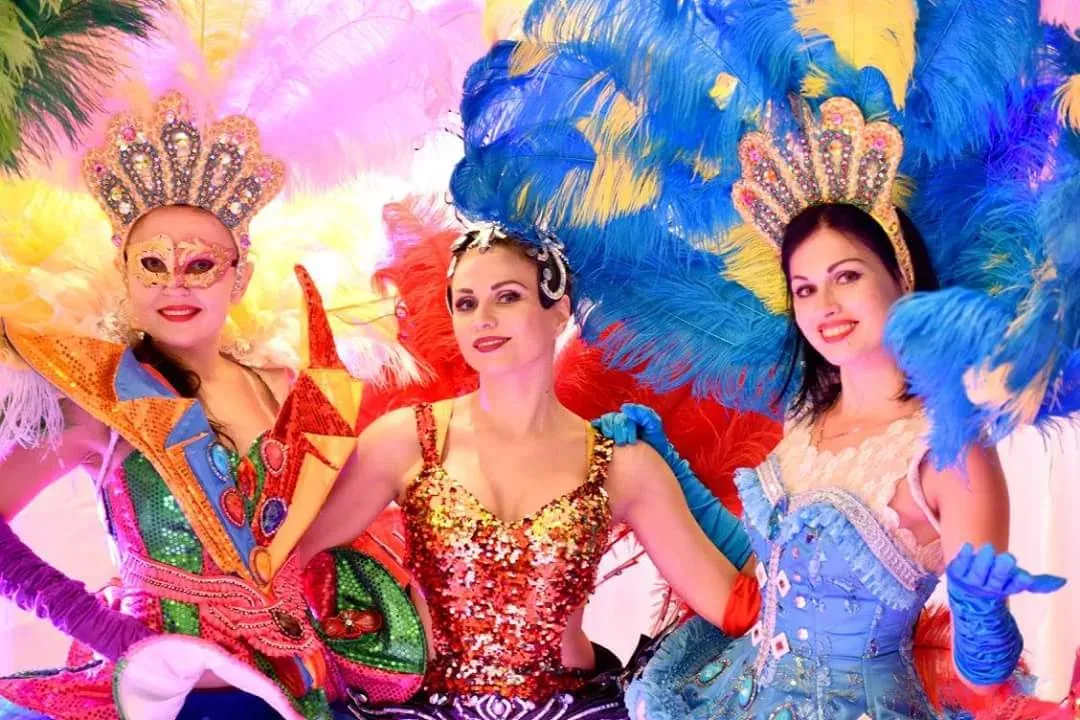Three performers in jewelled costumes and tall feathered headdresses