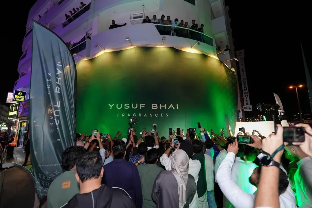 Crowd filming a shop facade washed in green light during an evening opening