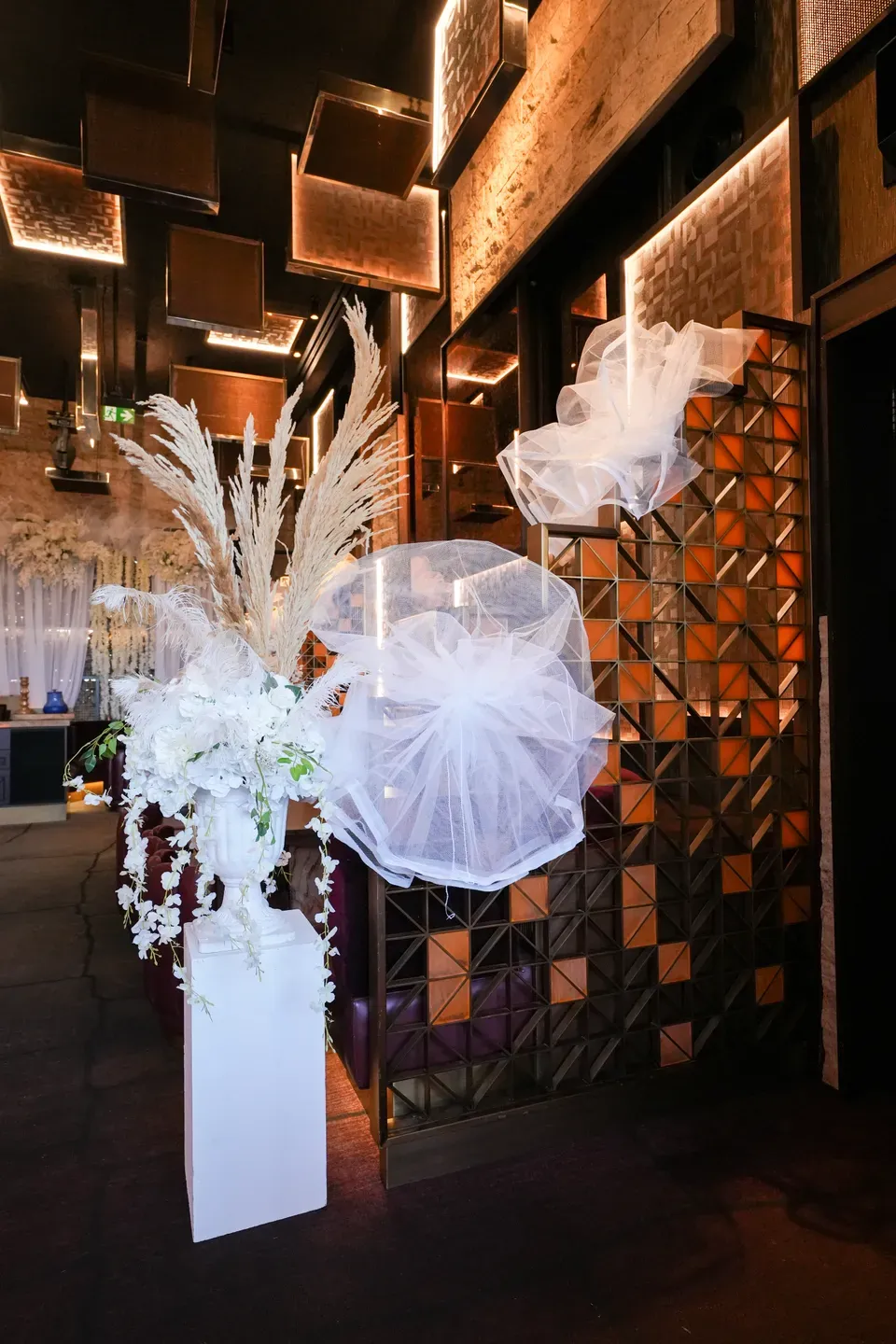 Pampas and orchid plinth with two tulle puffs against a bronze tiled wall