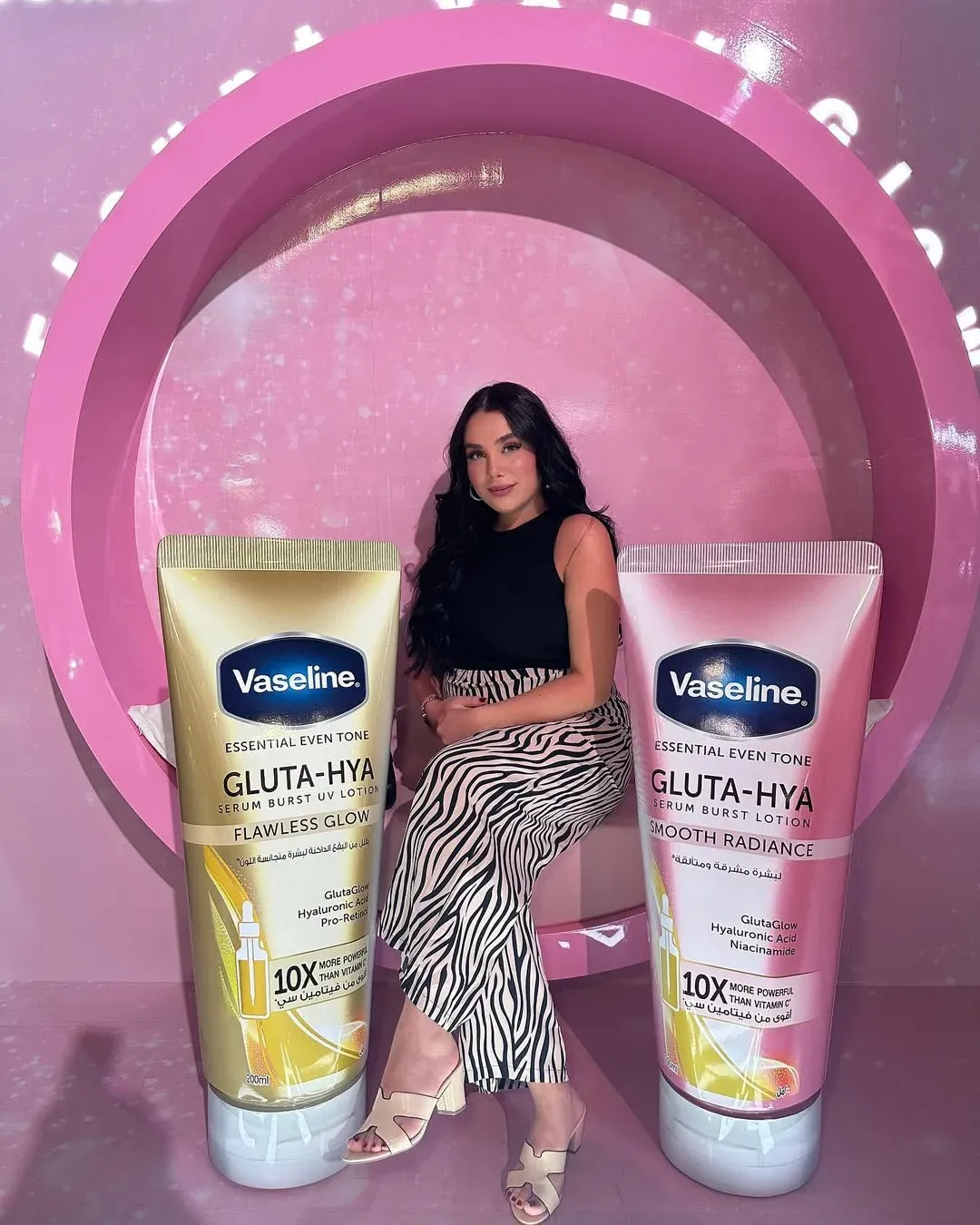 Guest standing between two oversized product tubes in front of a pink arch