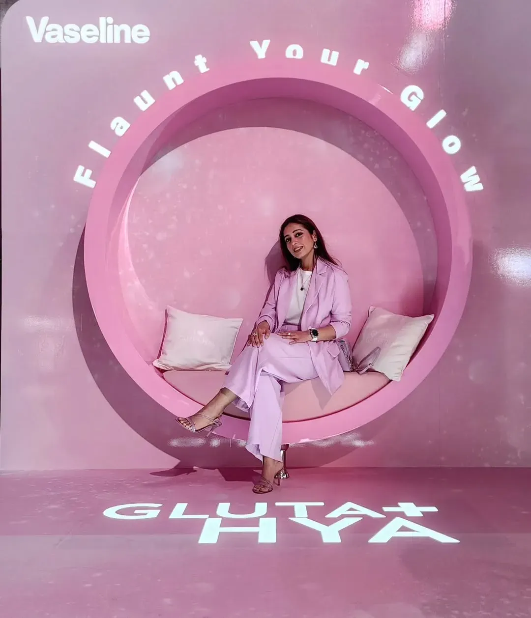 Guest seated inside a large pink circular swing seat on a pink branded set